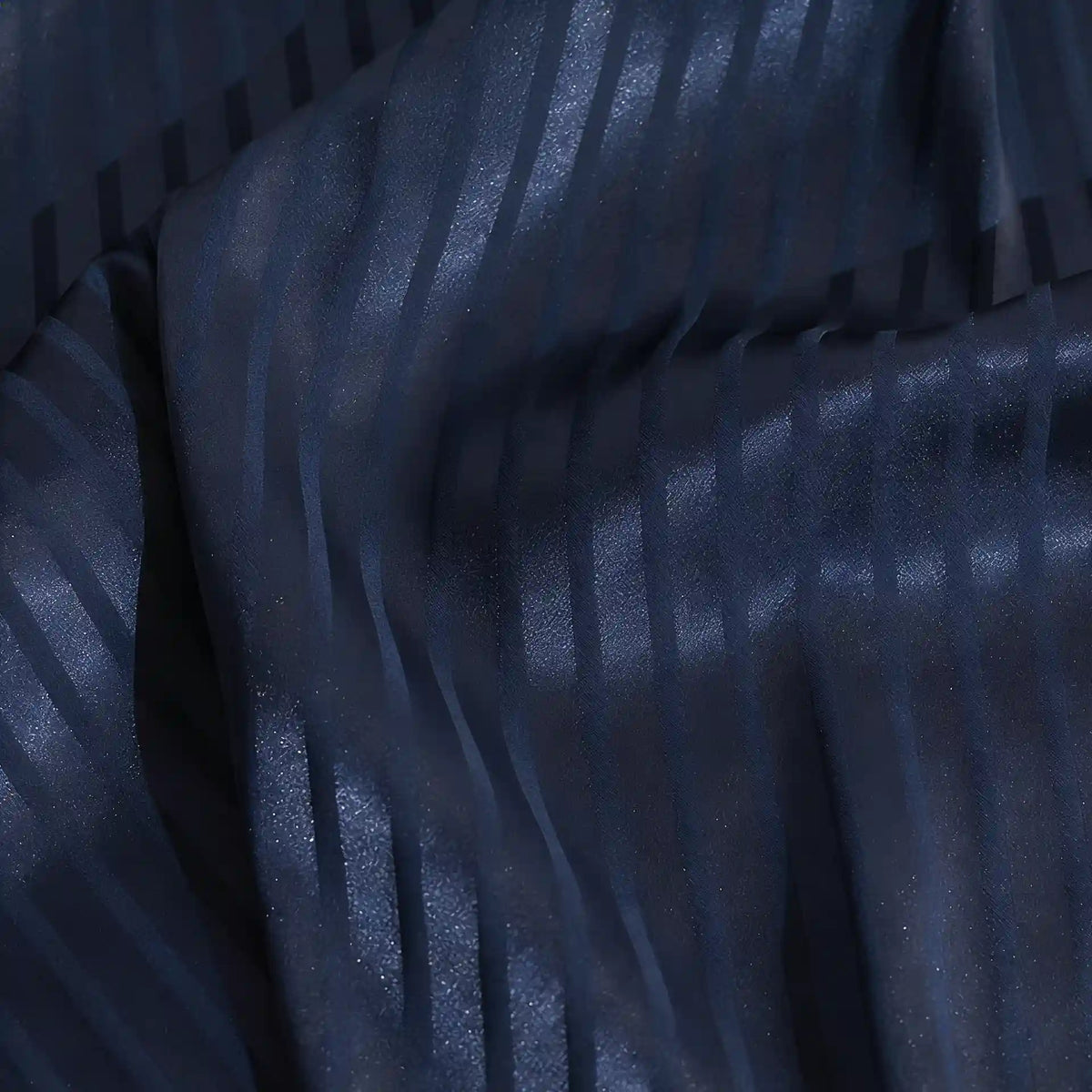 Un gros plan du tissu satin jacquard rayé coloré au mètre de Longan Craft France montre des rayures verticales subtilement brillantes et mates, avec des plis doux et une légère brillance - une matière satinée idéale pour la confection de robes.