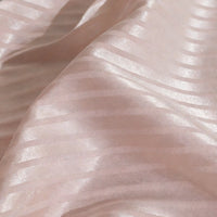 Gros plan sur le Tissu satin jacquard rayé coloré au mètre de Longan Craft France : satin rose pâle avec alternance de rayures mates et brillantes, drapé doux, brillance subtile - idéal pour les robes et les projets de couture créatifs.