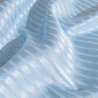 Gros plan sur le tissu satin jacquard rayé coloré au mètre de Longan Craft France, qui présente des motifs rayés semi-transparents et brillants. Le drapé doux met en valeur sa texture et convient parfaitement à la confection de robes.