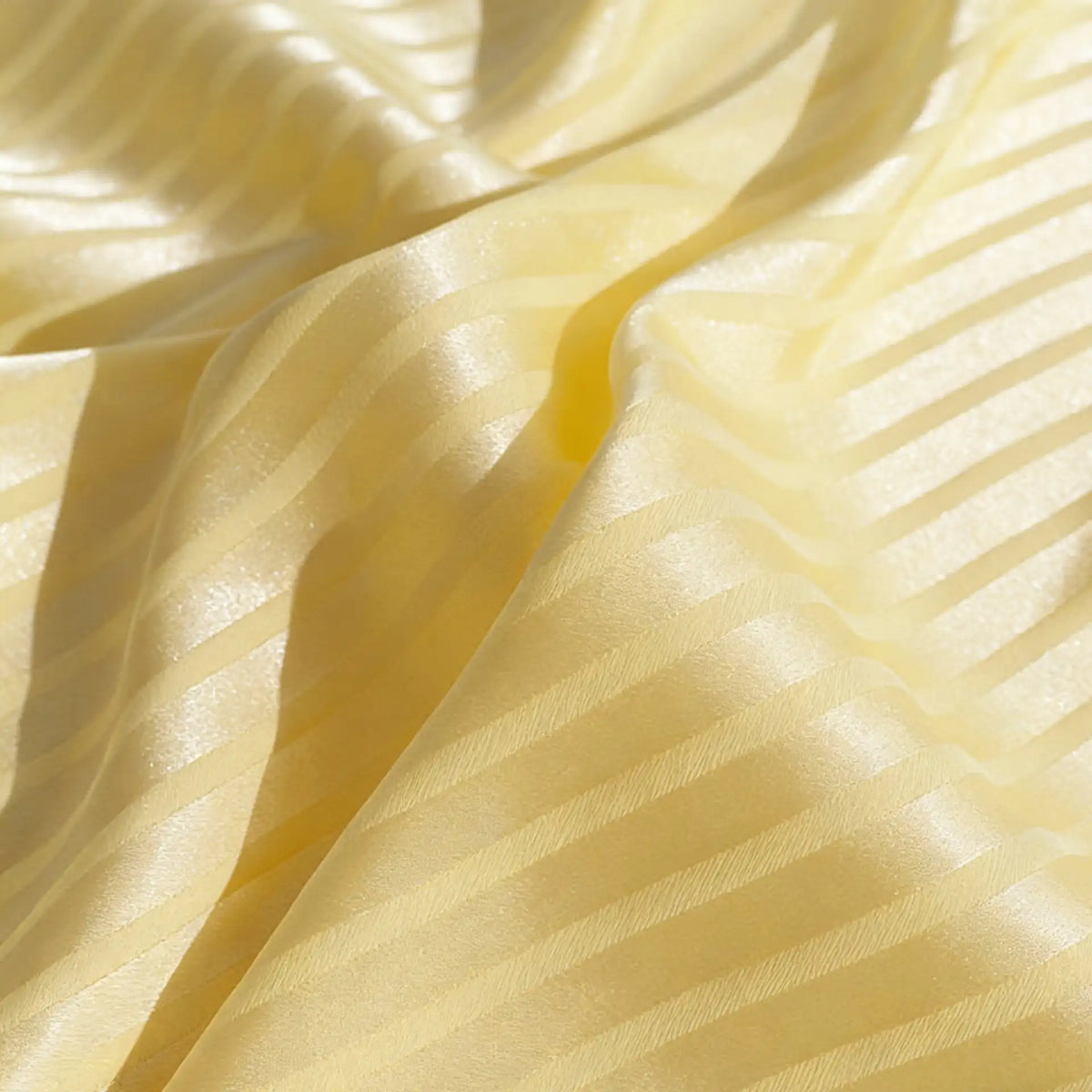 Gros plan sur le Tissu satin jacquard rayé coloré au mètre de Longan Craft France, qui présente une alternance de bandes diagonales mates et brillantes avec des plis doux - idéal comme matière satinée pour confection de robes.
