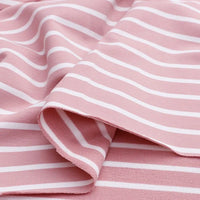L'image montre un morceau de Tissu French Terry extensible rayé coloré de Longan Craft France, un tissu de coton rose doux avec des rayures blanches régulièrement espacées, idéal pour les sweatshirts et disponible au mètre.