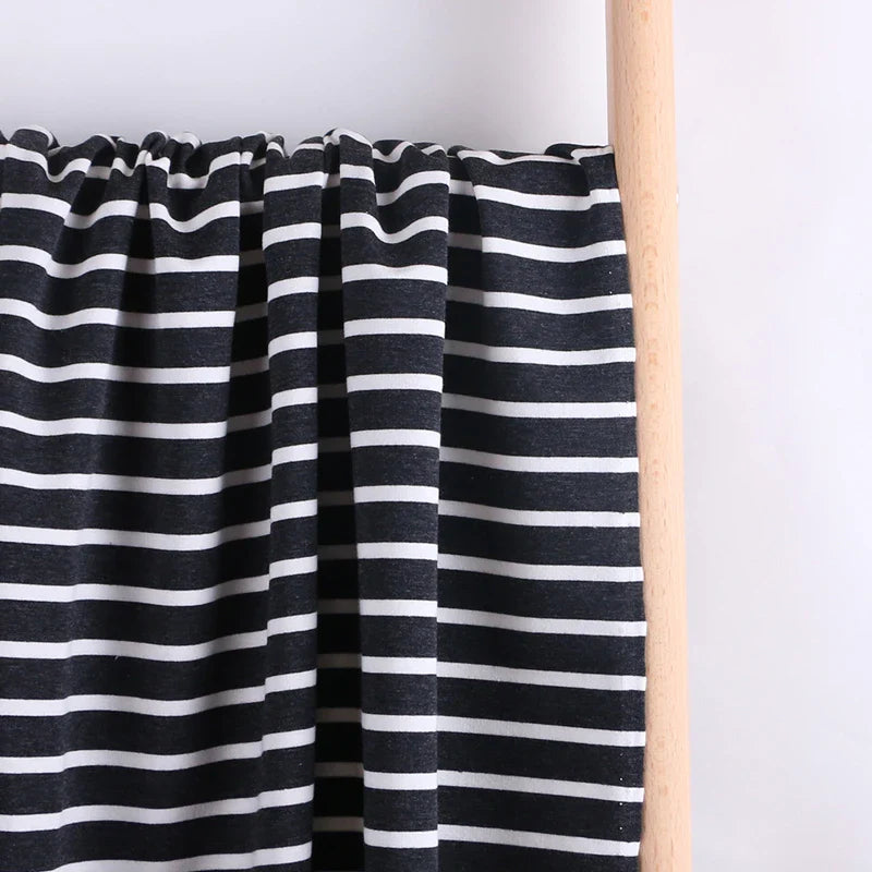 Un échantillon de Tissu French Terry extensible rayé coloré au mètre de Longan Craft France, un tissu de coton rayé idéal pour les sweatshirts, est drapé sur une tige de bois sur un fond blanc uni.