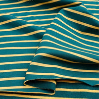 Gros plan sur le French Terry extensible de Longan Craft France, composé d'un tricot de coton sarcelle avec des rayures jaunes régulièrement espacées. Le tissu rayé coloré, idéal pour les sweatshirts, est montré avec des plis doux et des couches superposées douces.