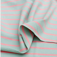 Le Longan Craft France Tissu French Terry extensible rayé coloré au mètre est un coton tricoté à fond vert clair avec des rayures roses horizontales, idéal pour sweatshirts, doux et flexible, livré légèrement froissé.