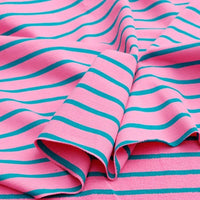 Le tissu French Terry extensible rayé coloré de Longan Craft France, en coton tricoté idéal pour sweatshirts, présente des rayures turquoise régulières sur fond rose, drapé et légèrement plié.