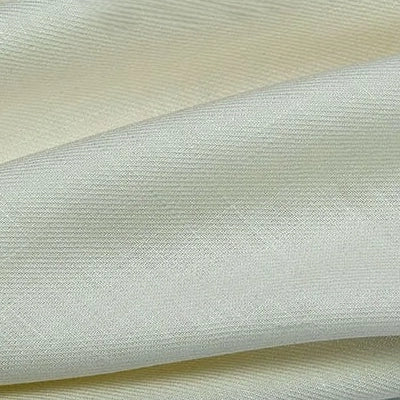 Un gros plan du Tissu lyocell sergé coloré au mètre de Longan Craft France montre un tissu crémeux, 100 % lyocell, avec une texture subtile de côtes diagonales, des plis doux et un aspect lisse et mat, idéal pour des costumes confortables et durables.