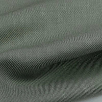 Gros plan sur le tissu lyocell sergé gris-vert coloré au mètre de Longan Craft France. Ce textile durable 100 % lyocell présente un tissage visible et des plis souples, idéal pour des costumes confortables et élégants.
