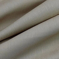 Un gros plan sur le tissu lyocell sergé beige plié de Longan Craft France montre sa texture lisse et son subtil motif à chevrons diagonaux. Tissu lyocell 100 % durable, vendu au mètre, idéal pour des costumes confortables.
