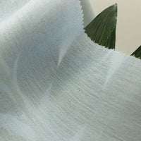 Gros plan sur Tissu en viscose challis multicolore au mètre de Longan Craft France, un tissu léger et respirant en viscose-polyester au motif subtil et à la texture douce, drapé sur des feuilles vertes pour des chemises protégeant du soleil.