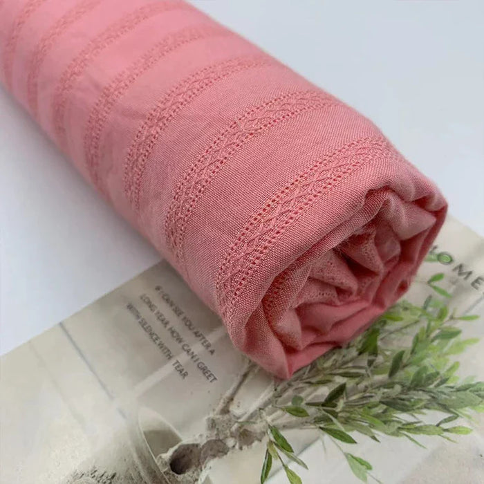 Gros plan sur le tissu dobby en viscose colorée au mètre de Longan Craft France, un jacquard coton-rayonne idéal pour les robes de bricolage, avec des lignes piquées et une finition douce et texturée, enroulé sur un magazine avec l'image d'un petit arbre.