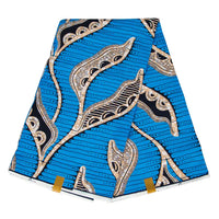 Tissu wax africain Ankara plié de Longan Craft France, avec un fond bleu, des motifs abstraits de feuilles noires, beiges et blanches ainsi que des rayures horizontales. Livré avec deux étiquettes dorées attachées aux coins inférieurs.