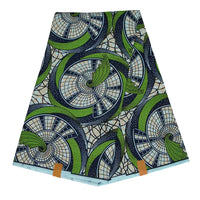 Un pli Longan Craft France Tissu wax africain Ankara coloré au mètre présente un motif géométrique en spirale et courbé dans des tons vert, bleu marine, crème et bleu clair. Deux étiquettes de couleur havane sont fixées sur le bord inférieur.