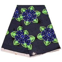 Un morceau plié de Tissu wax africain Ankara coloré au mètre par Longan Craft France, avec un imprimé géométrique et floral bleu-vert, des accents noirs, et des formes de feuilles sur un fond noir pointillé - parfait pour divers styles vestimentaires.