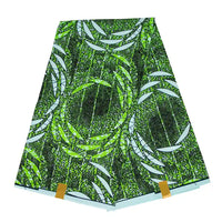 Un morceau plié de Tissu wax africain Ankara coloré au mètre par Longan Craft France, avec un motif géométrique abstrait vert, noir et blanc composé de lignes et de formes courbes qui se chevauchent, présenté sur un fond blanc.