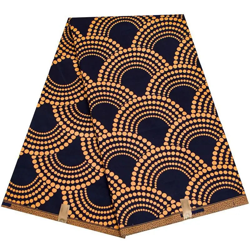 Le Longan Craft France Tissu wax africain Ankara coloré au mètre présente des demi-cercles en pointillés orange sur fond bleu foncé et est maintenu par deux clips dorés - parfait pour les styles vestimentaires branchés.