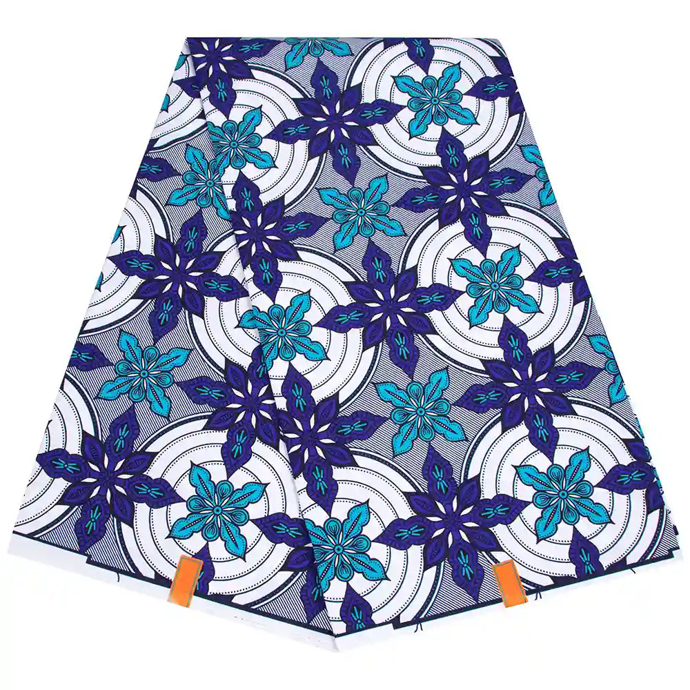 Un morceau plié de Tissu wax africain Ankara coloré au mètre par Longan Craft France présente des motifs floraux bleus et sarcelles sur des cercles blancs et noirs, avec deux étiquettes orange attachées au bord inférieur.