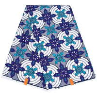 Un morceau plié de Tissu wax africain Ankara coloré au mètre par Longan Craft France présente des motifs floraux bleus et sarcelles sur des cercles blancs et noirs, avec deux étiquettes orange attachées au bord inférieur.