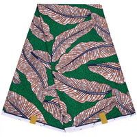 Un Tissu wax africain Ankara plié de Longan Craft France, avec un fond vert et de grandes feuilles beiges et noires soulignées de blanc, comporte deux étiquettes dorées en bas - parfait pour les styles vestimentaires à la mode.