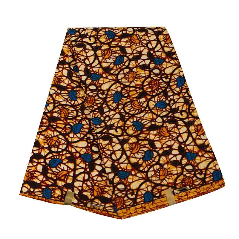 Un pli Longan Craft France Tissu wax africain Ankara avec des tourbillons noirs, un fond jaune orangé et des formes bleues est soigneusement disposé sur une surface blanche. Textile tendance d'Ankara, vendu au mètre pour divers styles vestimentaires.