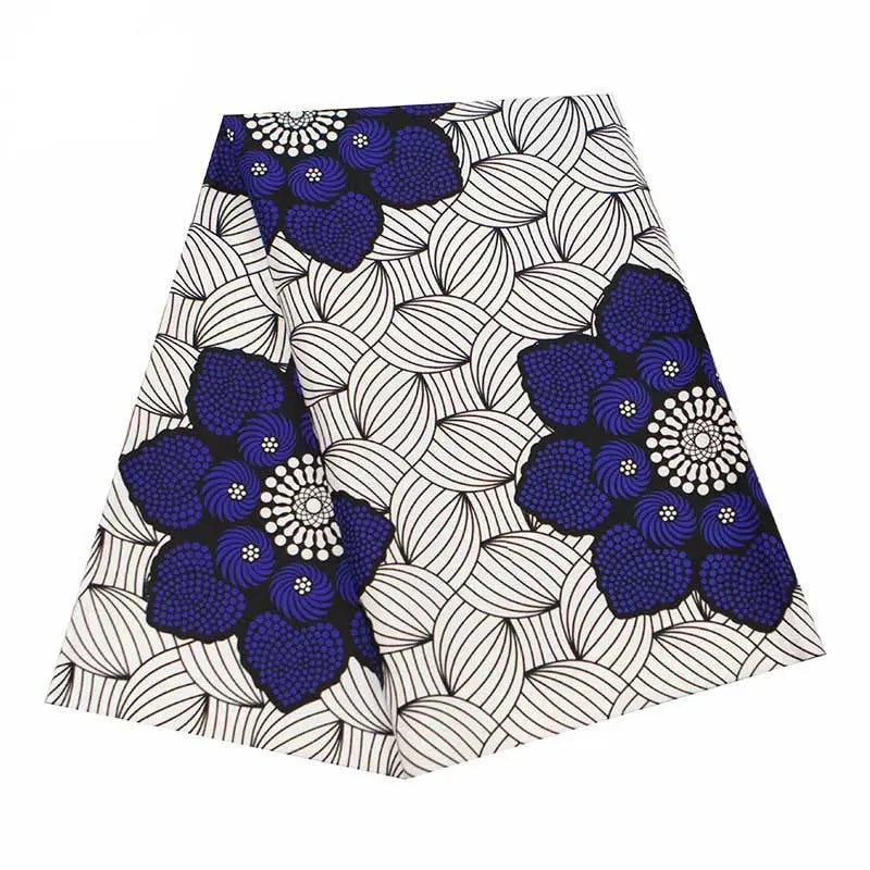 Tissu wax africain Ankara coloré au mètre de Longan Craft France, avec un motif répétitif de grandes fleurs bleu foncé et noires sur fond de feuilles blanches circulaires entrelacées et cernées de noir. Idéal pour divers styles vestimentaires.