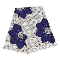 Tissu wax africain Ankara coloré au mètre de Longan Craft France, avec un motif répétitif de grandes fleurs bleu foncé et noires sur fond de feuilles blanches circulaires entrelacées et cernées de noir. Idéal pour divers styles vestimentaires.