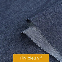 Gros plan sur un tissu denim bleu lisse avec des bords en zigzag. Une étiquette jaune indique "Fin, bleu vif". Issue de la collection Tissu denim coton au mètre de Longan Craft France, cette toile est idéale pour les projets nécessitant des denims de différents grammages.