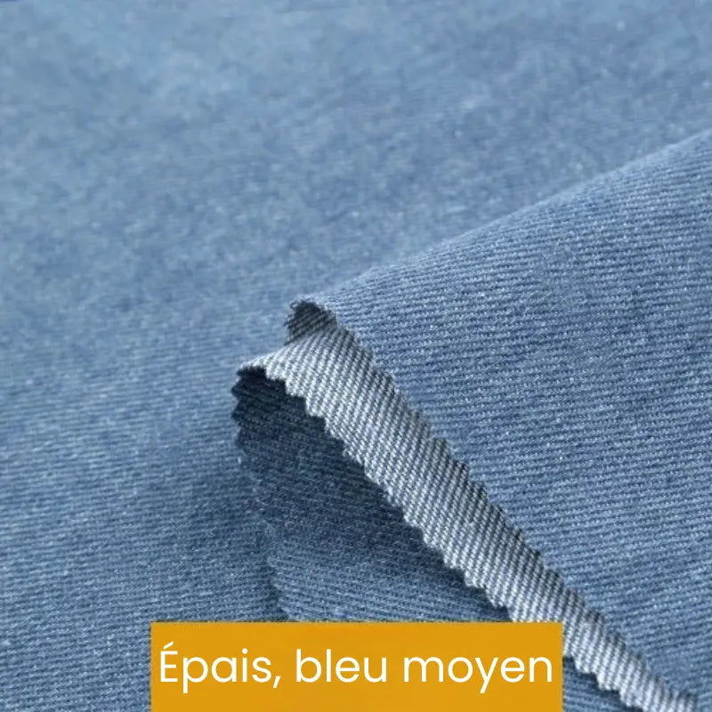 Gros plan sur le tissu denim coton au mètre de Longan Craft France, bleu moyen et épais avec un tissage visible. Une étiquette jaune en bas indique "Épais, bleu moyen". Disponible en différents poids, idéal pour les jeans.