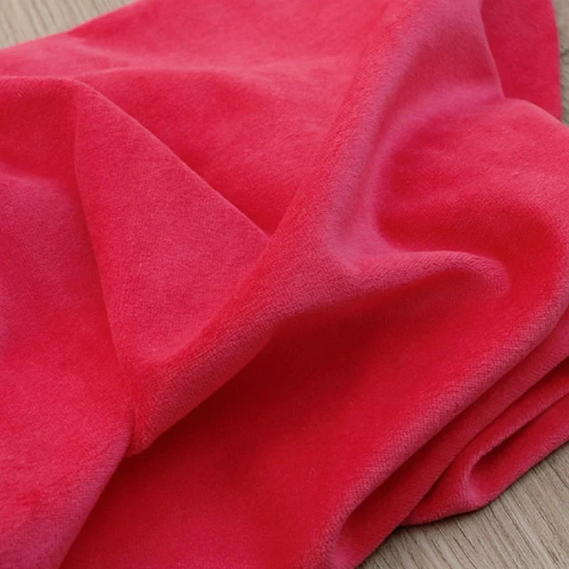 Un Velours de coton et polyester doux au mètre de Longan Craft France est drapé sur du bois, mettant en valeur sa brillance subtile - parfait tissu velours uni pour ameublement, habillement ou couture.
