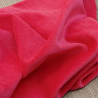 Un Velours de coton et polyester doux au mètre de Longan Craft France est drapé sur du bois, mettant en valeur sa brillance subtile - parfait tissu velours uni pour ameublement, habillement ou couture.