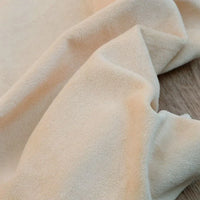 Gros plan sur Velours de coton et polyester doux au mètre de Longan Craft France, un tissu velours uni en maille, beige, à surface douce et légèrement texturée-idéal pour ameublement, habillement et projets de couture.