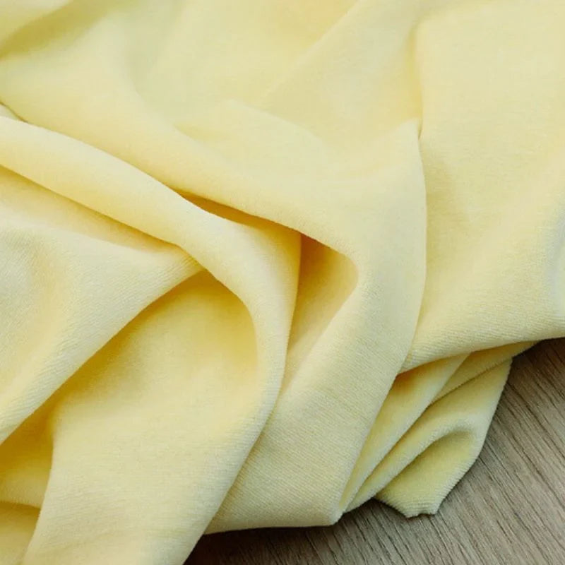 Le Velours de coton et polyester doux au mètre Longan Craft France, tissu velours uni lisse et léger pour ameublement ou couture, est présenté légèrement froissé sur une surface en bois.