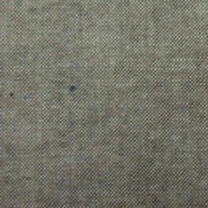 Gros plan sur le Tissu chambray denim en coton au mètre de Longan Craft France, un tissu de coton fin, gris-brun avec de petites taches foncées et un tissage visible, idéal pour les chemises d'été.