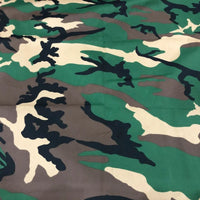 Un gros plan de Tissu camouflage en coton au mètre de Longan Craft France montre des impressions irrégulières vertes, brunes, beiges et noires, idéales pour les pantalons tendance hip-hop ou les équipements de plein air durables.