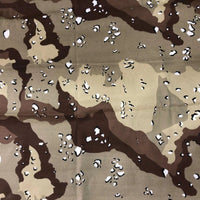 Un gros plan du tissu camouflage en coton au mètre de Longan Craft France montre un mélange irrégulier de motifs bruns, havanes, beiges et blancs, idéal pour les pantalons tendance style hip-hop.