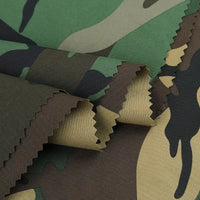 Des couches de tissu sergé camouflage en coton au mètre vert, marron, beige et noir de Longan Craft France présentent des bords coupés en zigzag. Durable et brossé, il est idéal pour créer des pantalons, des vestes, des chaussures ou des casquettes.