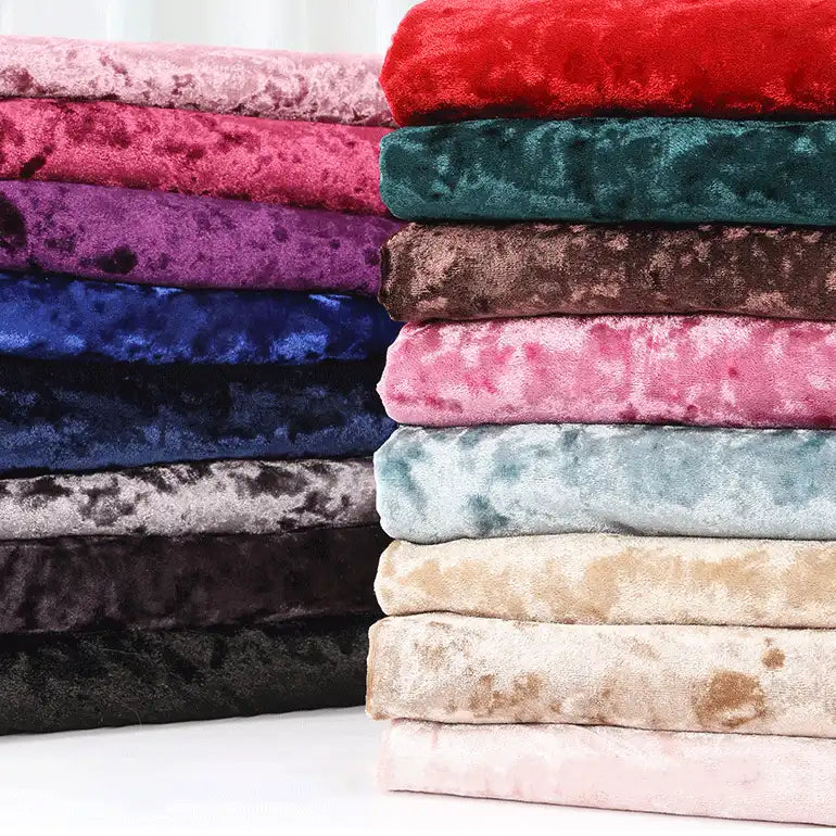 Une pile de Longan Craft France Tissu en velours froissé au mètre en rouge, violet, bleu, marron, rose, gris, noir, beige et bleu clair est disposée en deux colonnes sur un fond uni.