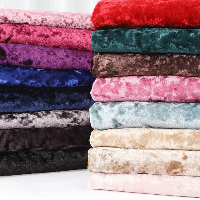 Une pile de Longan Craft France Tissu en velours froissé au mètre en rouge, violet, bleu, marron, rose, gris, noir, beige et bleu clair est disposée en deux colonnes sur un fond uni.