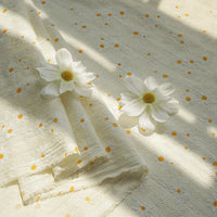 Le tissu dobby imprimé marguerites de Longan Craft France, en coton texturé, présente de petites fleurs jaunes et blanches. Idéal pour vêtements d'été, il est confortable et vendu au mètre : parfait pour vos créations estivales.