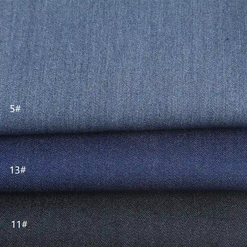 Trois échantillons pliés de Tissu sergé de viscose coloris denim Longan Craft France, étiquetés "5#", "13#", et "11#", montrent un tissu extensible en viscose de couleur bleu clair à bleu foncé dégradé-chic, idéal pour la confection de vestes ou les projets créatifs.