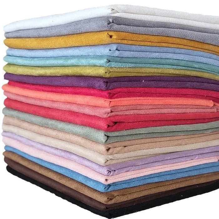 Une pile colorée de tissu suédine double face au mètre de Longan Craft France, disponible en jaune, bleu, vert, rouge, rose, violet, beige, marron, gris, noir et blanc - idéal pour les housses de canapé, les sacs et les doublures.