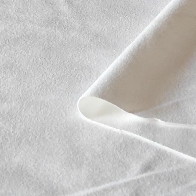 Gros plan sur le tissu suédine double face au mètre de Longan Craft France, un tissu souple en daim microfibre blanc avec un coin relevé, idéal pour les housses de canapé, les sacs et les doublures.