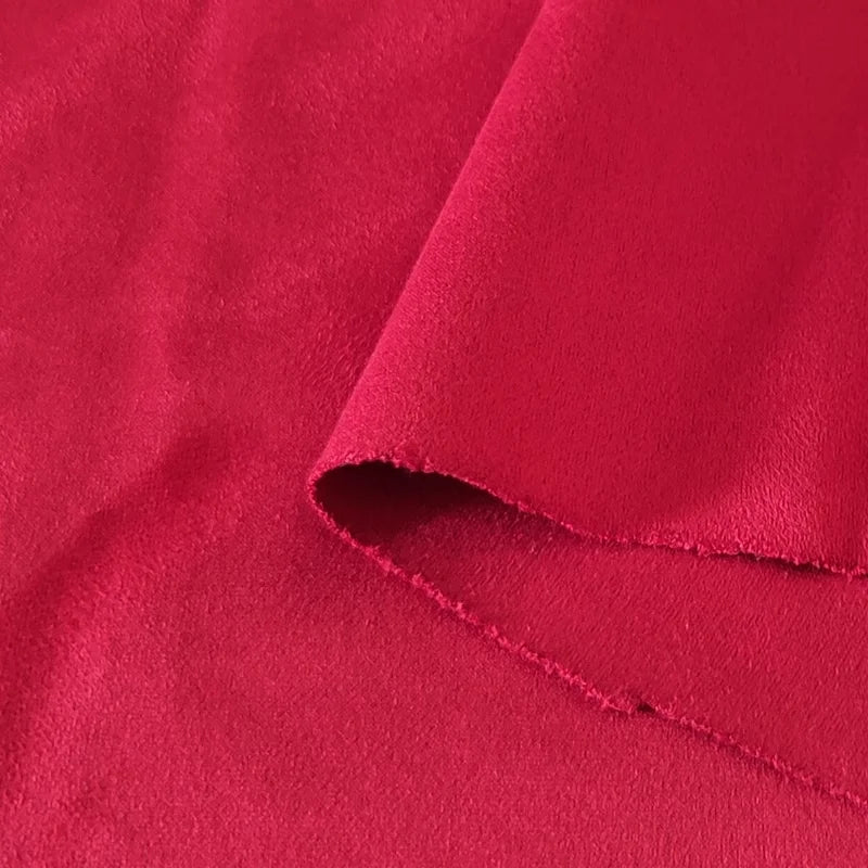 Gros plan sur le tissu suédine double face au mètre de Longan Craft France, un tissu microfibre rouge imitant le daim pour les canapés, les sacs et les doublures, montrant sa texture douce et son bord non fini.