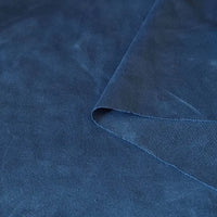 Gros plan sur le tissu suédine double face au mètre de Longan Craft France en bleu foncé, montrant sa texture douce en microfibre et un coin plié, idéal pour les housses de canapés, les sacs et les doublures.
