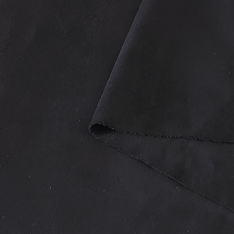 Gros plan sur le tissu suédine noir double face au mètre de Longan Craft France, montrant un coin plié et mettant en valeur sa texture microfibre douce et mate, idéale pour les housses de canapés, les sacs et les doublures.