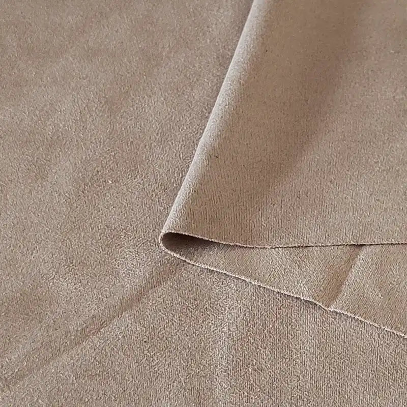 Un gros plan du Tissu suédine double face au mètre de Longan Craft France montre un suédine microfibre beige avec un coin plié, révélant à la fois le recto et le verso - parfait pour les tissus d'ameublement, les sacs et les doublures.