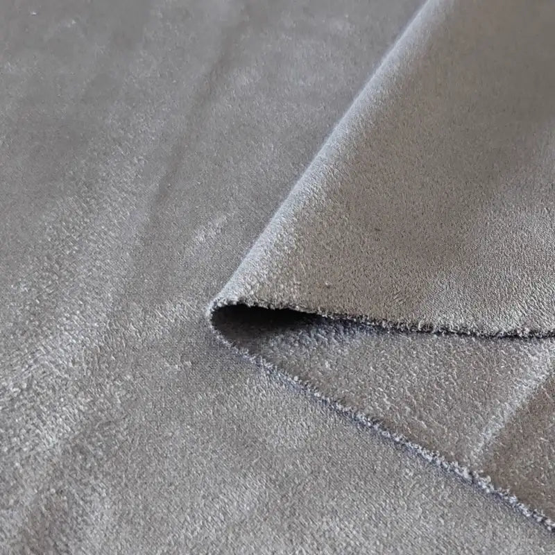 Un gros plan du tissu suédine double face au mètre de Longan Craft France montre un coin plié, mettant en évidence la texture douce de la microfibre et la finition en faux daim, idéale pour les housses de canapé, les sacs et les doublures.