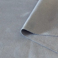 Un gros plan du tissu suédine double face au mètre de Longan Craft France montre un tissu daim microfibre gris avec un coin plié, mettant en valeur la texture et l'épaisseur - idéal pour les housses de canapés, les sacs et les doublures.