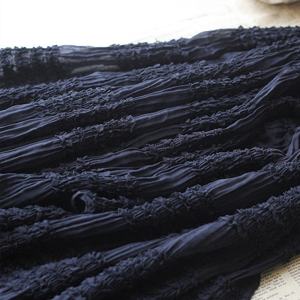 Gros plan sur le tissu mousseline plissé extensible au mètre de Longan Craft France en noir, montrant sa texture ruchée horizontale sur une surface plane et claire. Idéal pour les robes à plis ; existe également en blanc, abricot et rose.