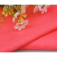 Gros plan sur le pliage de Suédine unie embossée au mètre de Longan Craft France, un tissu en daim synthétique de première qualité, avec des fleurs artificielles roses et jaunes disposées sur le dessus.