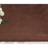 Un morceau de Suédine unie embossée au mètre de Longan Craft France, un tissu en daim synthétique de qualité supérieure, est posé à plat sur de la dentelle blanche. Des roses blanches avec des feuilles vertes sont partiellement visibles en haut à gauche.